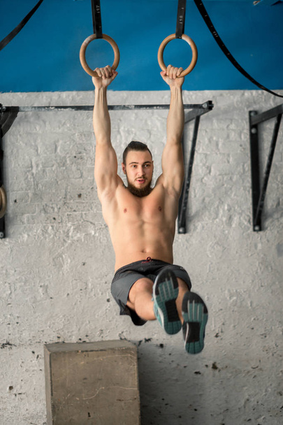 Muscle-up exercise athletic man doing intense workout at gym on gymnastic rings - Photo, Image