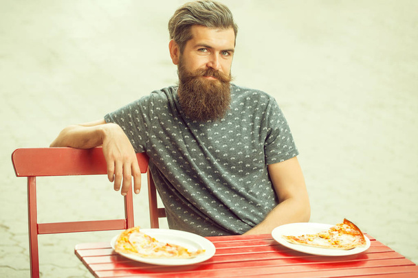 красивый бородатый мужчина с пиццей в кафе
 - Фото, изображение