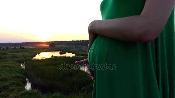 Hermosa puesta de sol y el estómago embarazada en vestido verde
. - Imágenes, Vídeo