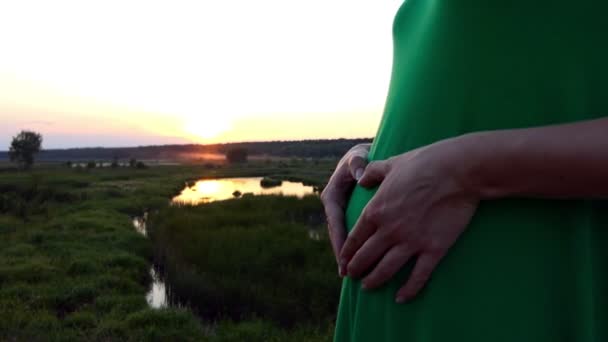 Srdce z rukou těhotná dívka při západu slunce. - Záběry, video