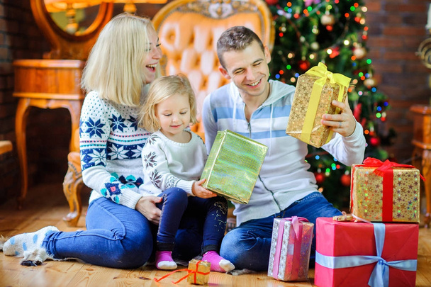 happy family sitting on the floor near the Christmas tree, giving each other presents and having fu - Фото, зображення