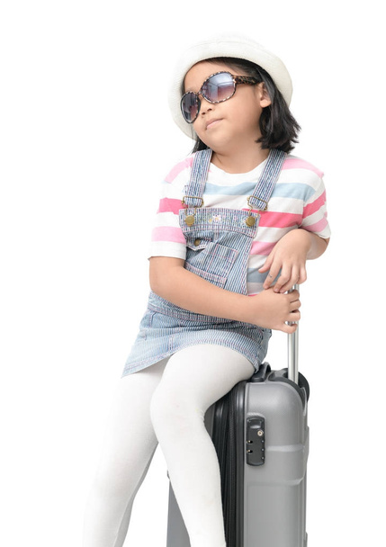 かわいいアジアの女の子の肖像画は、サングラスを着用し、スーツケースの上に座る  - 写真・画像