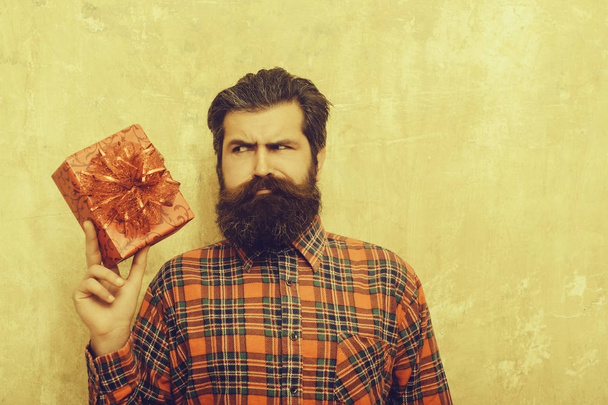 sad bearded man with red gift box with bow - Zdjęcie, obraz