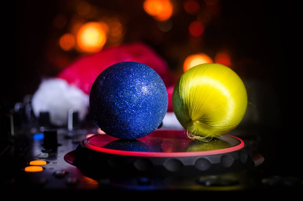 DJ keverő fejhallgató, a sötét éjszakai háttér karácsonyfa Szilveszter. Zár-megjelöl kilátás-új év elemek vagy szimbólumokat (Mikulás, hóember, kutya 2018, díszdobozban) Dj asztalon. - Fotó, kép