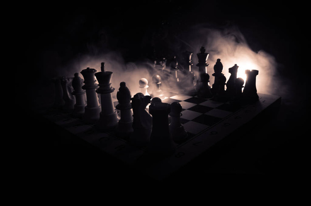 Концепция шахматной настольной игры бизнес-идей, конкуренции и стратегических идей. Шахматные фигуры на темном фоне с дымом и туманом. Селективный фокус
 - Фото, изображение