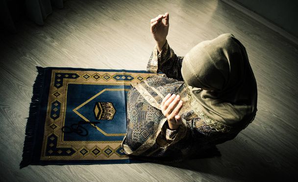 Muslim woman praying for Allah muslim god at room near window. Hands of muslim woman on the carpet praying in traditional wearing clothes, Woman in Hijab, Carpet of Kaaba, Selective focus, toned - Fotografie, Obrázek