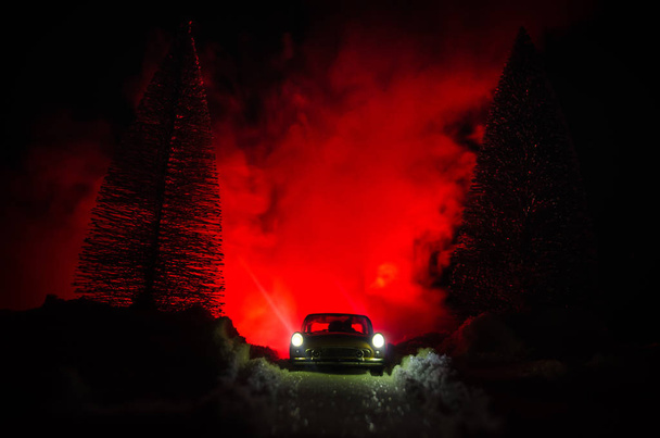 Luzes de carro à noite em pinhal com neve. Luzes de carro na floresta de inverno. Decoração de brinquedo. Foco seletivo
 - Foto, Imagem