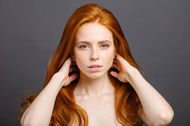 redhead woman holding her healthy and shiny hair, studio grey - Foto, immagini