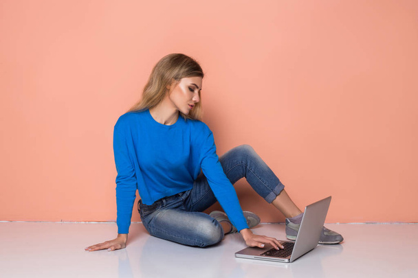 Serious woman working with laptop while sitting on floor isolated - 写真・画像