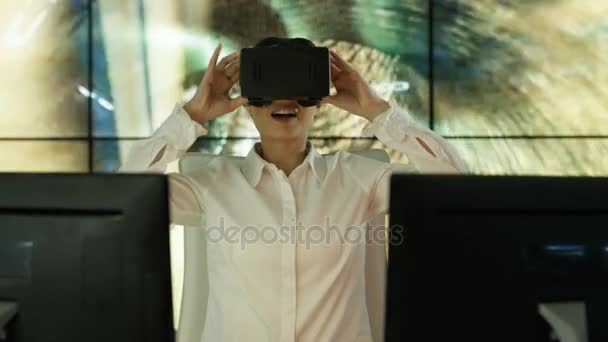 4K Businesswoman wearing virtual reality viewer at her desk with animated graphic of a data tunnel in background - Filmati, video