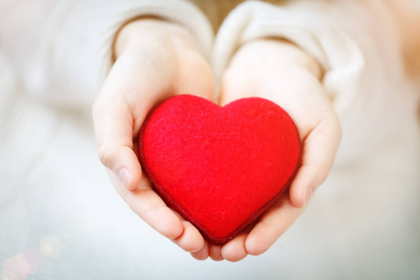 Red heart in hands of the little girl. Symbol of love and family.Valentines day card. Mothers day. Backgrounds for social posters. Selective focus. - Fotografie, Obrázek