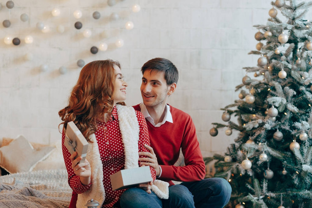 Adorable pareja abriendo regalos de Navidad sonriendo
 - Foto, imagen