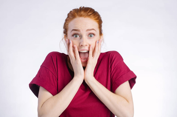 Surprised redhead woman wide open mouth and touching her head. white background - Фото, изображение
