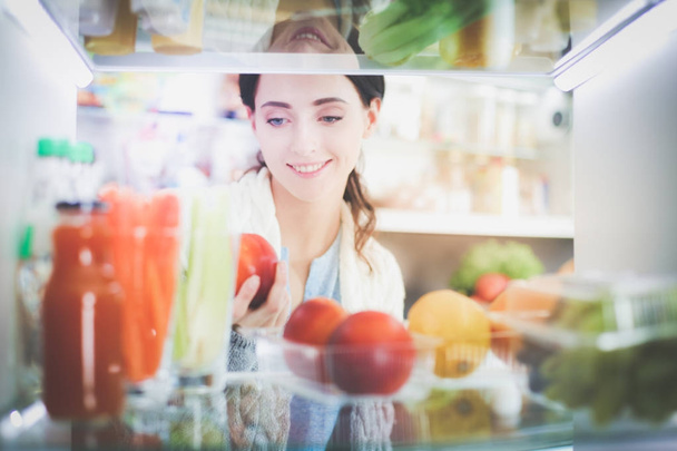 Portrait de femme debout près d'un réfrigérateur ouvert rempli d'aliments sains, de légumes et de fruits. Portrait de femme - Photo, image