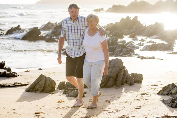 charmant couple d'aînés âgés de 60 ou 70 ans à la retraite marchant heureux et détendu sur la plage bord de mer dans le vieillissement romantique ensemble
  - Photo, image