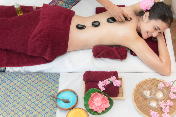 Asie beauté femme couchée sur lit de massage avec des pierres chaudes traditionnelles le long de la colonne vertébrale au spa thaïlandais et centre de bien-être, alors détendez-vous et mode de vie. Concept sain
 - Photo, image