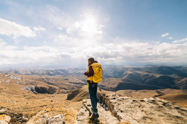 active girl travels along the Caucasian ridge with a yellow backpack, enjoys nature - Photo, image