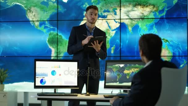 4K Liikemiehet keskustelevat suuri maailmankartta graafinen videoseinä, jossa pie kaavioita ja kaavioita näkyy tietokoneen näytöillä
 - Materiaali, video