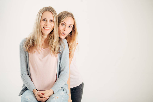 Surprised girl looking at her sister twin over white background - 写真・画像