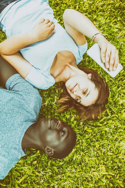 Para nastolatków mieszanej rasy kur na trawie patrząc każdego ot - Zdjęcie, obraz