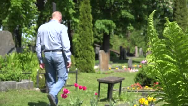 Yksinäinen mies istuu penkillä marmorista ristiin maan hautausmaalla. 4K
 - Materiaali, video