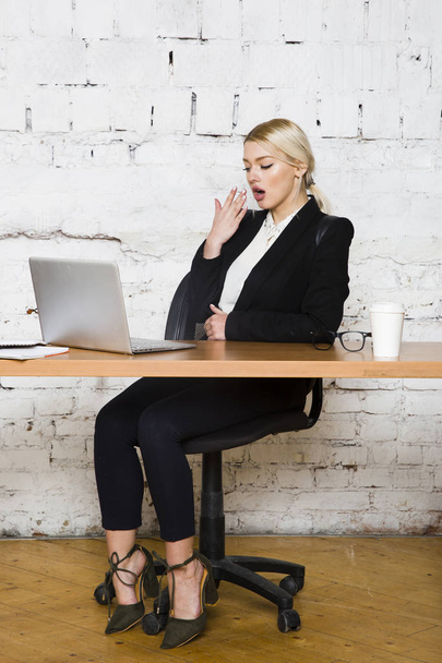 Young blond beauty businesswoman sitting at a office table with laptop, notebook and glasses in suit. Business concept. - Foto, Bild