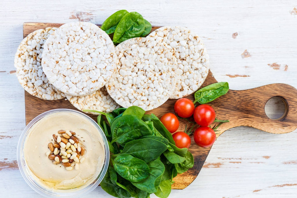 Healthy Snack from Rice Cakes with Hummus, Spinach and Tomatoes - Photo, Image