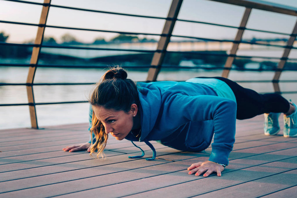 Woman doing push-ups by the river - Photo, Image