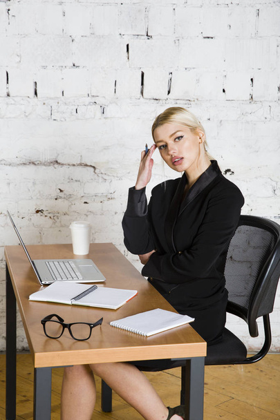 Young blond beauty businesswoman sitting at a office table with laptop, notebook and glasses in suit. Business concept. - Fotoğraf, Görsel