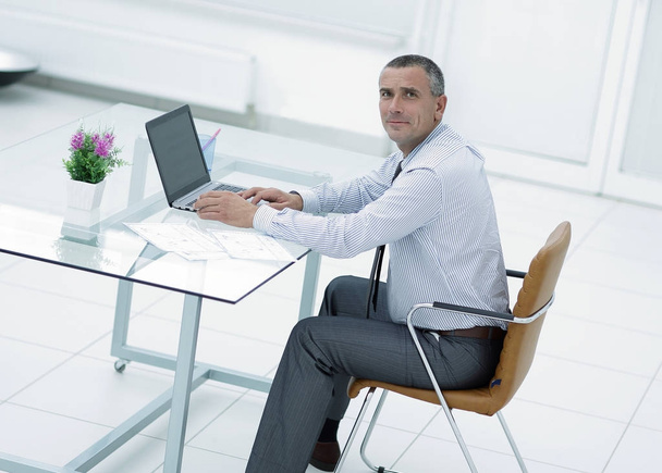smiling businessman sitting at Desk and looking at camera - Фото, зображення