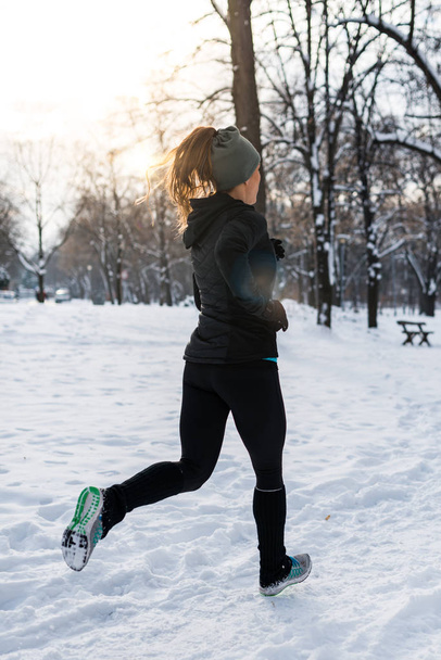 公園の冬の日の公園でジョギングの女性選手 - 写真・画像