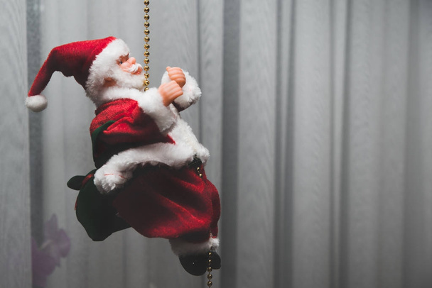 Noel Baba'nın görünümü. Oyuncak Noel Baba, kırmızı şapka, ellerini kaldırdı. Noel hediyeler, oyuncaklar vererek geliyor. Noel iklim kavramı. Mutluluk ve memnuniyet çocukların hediye alma. - Fotoğraf, Görsel