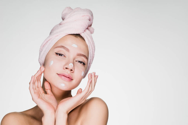 beautiful young girl with a pink towel on her head applied a useful cream on her face - Photo, Image