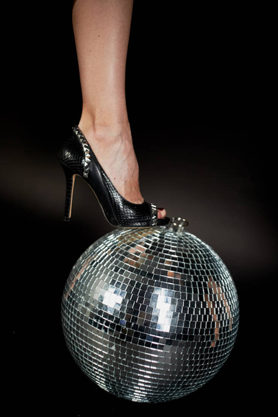 Disco ball , it female foot in shoes .A symbol of music, clubs and nightlife. Holidays and fun parties - Photo, image