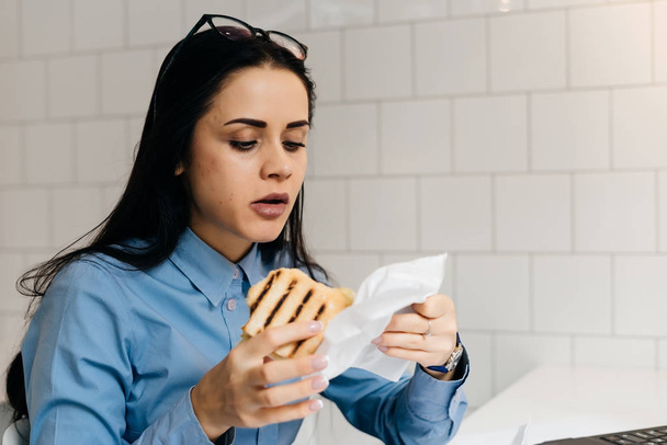 young beautiful brunette girl eating a sandwich at a cafe - Foto, immagini