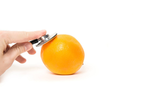 Checking, examining oranges, fruit. A man is examining citrus with a stethoscope. Examination of fruit freshness. Quality control. Bio fruit. The best and tested oranges. Isolated white background. - Foto, Bild