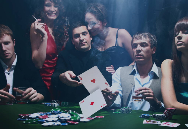 Poker players sitting around a table at a casino - Photo, image