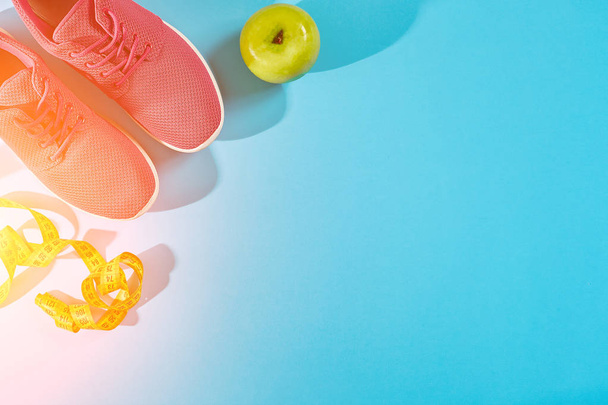 Sneakers con metro a nastro su fondo azzurro ciano. Centimetro in colore giallo vicino a scarpe da ginnastica rosa, primo piano. Ramponamento solare
 - Foto, immagini