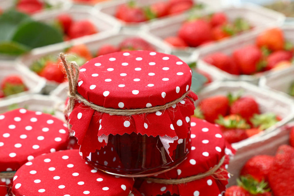 Frascos de mermelada roja sobre fresas frescas
 - Foto, imagen