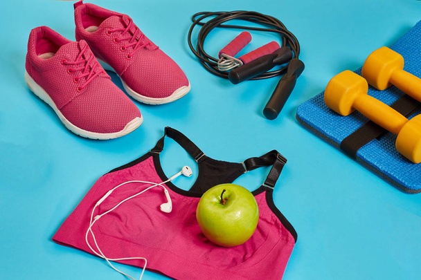 Flat lay of dumbbell, bottle of water, jump rope and sneaker, sport equipments, fitness items, top view - Photo, Image