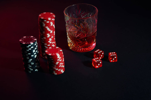 Poker chips and wine glass of cognac on dark table. Gambling - Фото, изображение