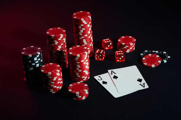 Red and black chips for gambling and playing cards on black background - Photo, Image