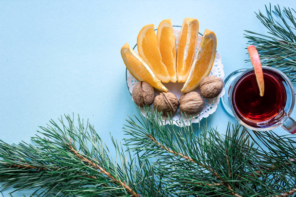 Hot mulled wine with orange, anise, cardamon and cinnamon on blue background. Christmas tree branches, gifts and cones. - Foto, Imagem