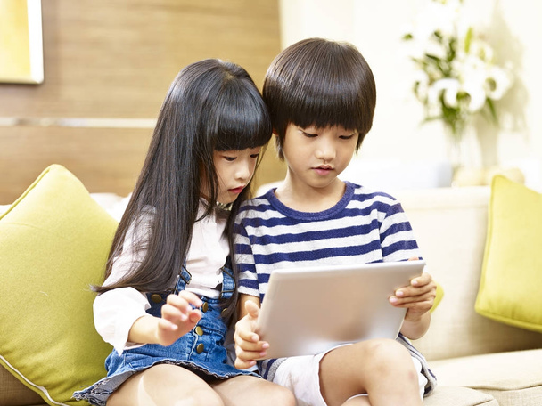 Ασιατικές αδελφός και αδελφή χρησιμοποιώντας ψηφιακό tablet μαζί - Φωτογραφία, εικόνα