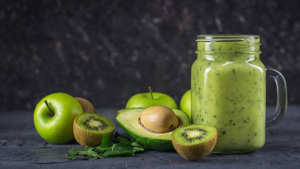 Smoothies from avocados, bananas, kiwi and herbs on a black table. Diet vegetarian food. - Photo, Image