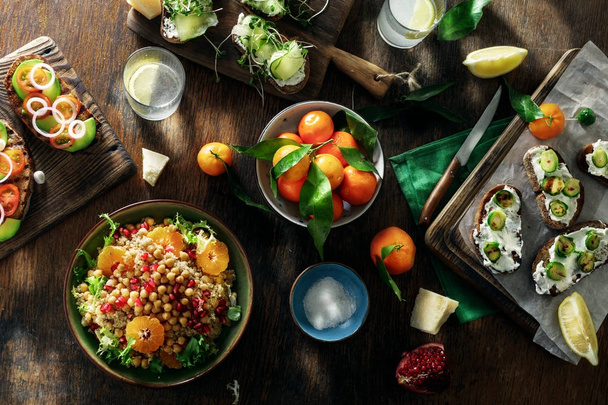Vegetarian food on a dark wooden table with homemade lemonade. Bruschetta with tomatoes, cucumbers, Brussels sprouts and salad with chickpeas and quinoa. Top view. - Fotoğraf, Görsel
