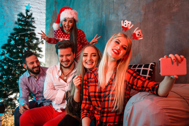 Amigos haciendo selfie mientras celebran la Navidad o Año Nuevo en casa
 - Foto, imagen