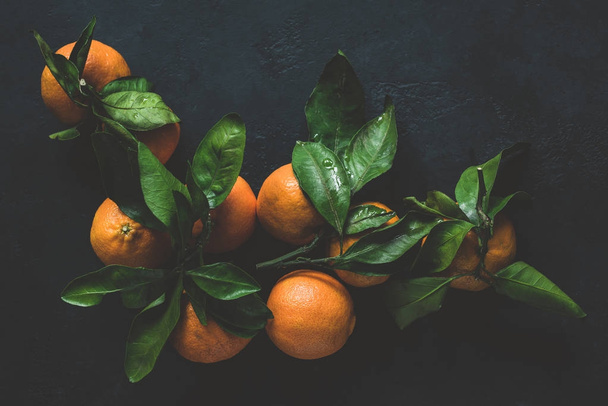 Tangerines or clementines with green leaf on dark background. Still life - Photo, image