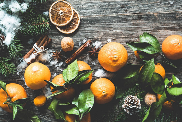 Christmas winter wallpaper or background with tangerines, snow and pine cones on old wooden backdrop - Foto, immagini