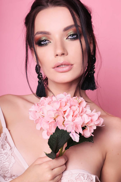 beautiful woman with dark hair and evening makeup with flowers - Fotó, kép